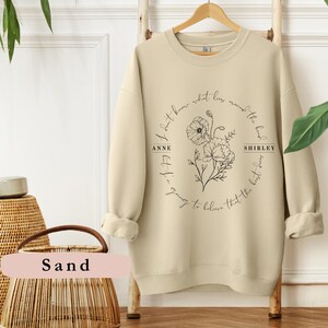 May include: A beige sweatshirt with a black floral design and the text "I don't know what lies around the bend.  But I'm going to believe that the best is yet to come."  The text is in a circle around the floral design.  The text "ANNE" and "SHIRLEY" are on either side of the floral design.