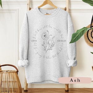 May include: Gray sweatshirt with a black floral design and the text "I don't know what lies around the bend but I'm going to believe that the best is yet to come" with the names "Anne" and "Shirley" on either side of the floral design.