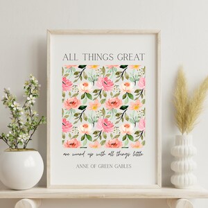 May include: A framed print with the text "ALL THINGS GREAT" and a floral pattern in pink, peach, and yellow on a light gray background. The quote "are wound up with all things little" is below the floral design, with "ANNE OF GREEN GABLES" below that.