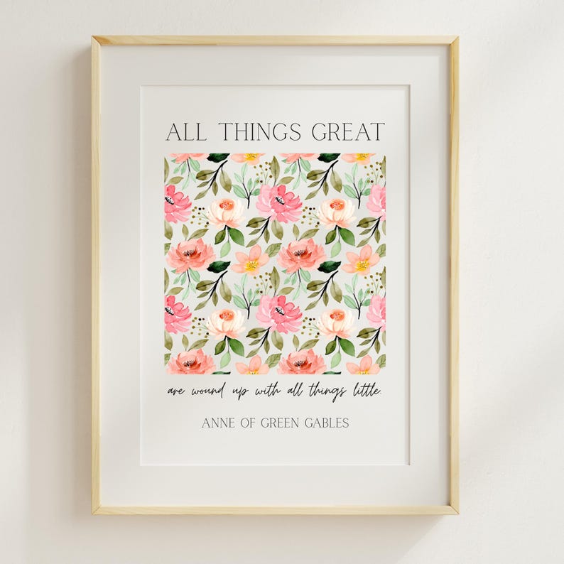 May include: A framed print featuring the quote "ALL THINGS GREAT are wound up with all things little. ANNE OF GREEN GABLES." The print has a floral pattern in pink, peach, and yellow, with green leaves on a light gray background. The frame is a light wood color.