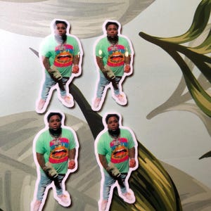 May include: Four stickers featuring a man wearing a green shirt with a colorful graphic print. The man is wearing blue jeans and white sneakers. The stickers are on a floral background.