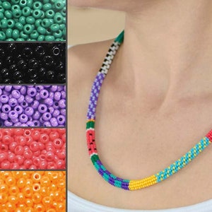 May include: A colorful beaded necklace with alternating stripes of green, purple, yellow, orange, and red beads. The necklace is made of small, round beads and is worn by a person.