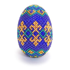 May include: A blue Easter egg decorated with a geometric pattern of gold and green beads.
