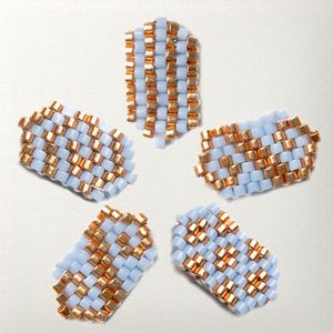 May include: Five beaded pieces in a light blue and gold color scheme. The beads are arranged in a woven pattern, creating a textured surface. The pieces are rectangular and appear to be components for jewelry or crafts.