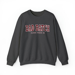 Puede incluir: Una sudadera gris oscuro con el texto "BAD BATCH" en letras rojas y blancas. Debajo del texto, "CLONE FORCE 99" en letras rojas más pequeñas.