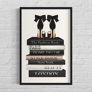 May include: Framed print showing a stack of books with titles including "The Fashion Book" and "Beauty." Two black high heels with bow details are on top. The print has a white background and a black frame.