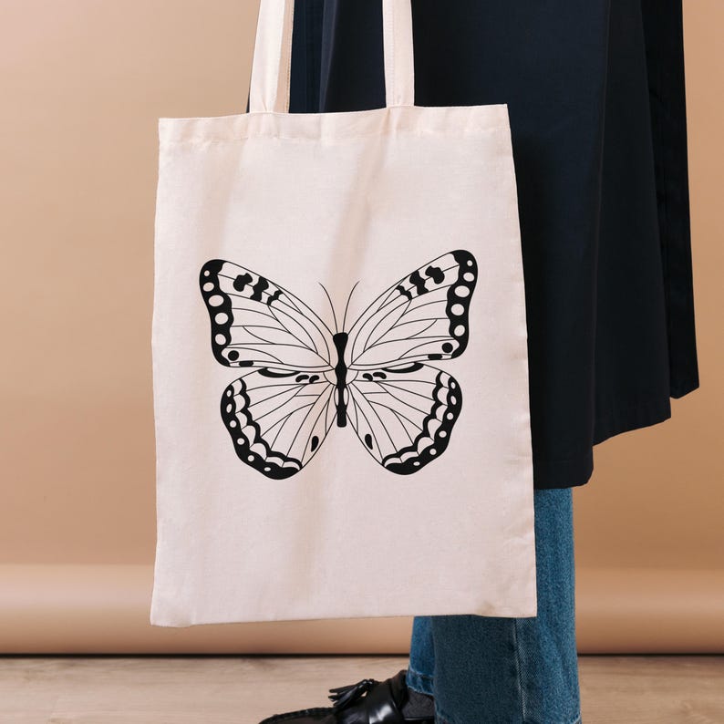 Mockup image showing one of the butterfly stamp designs on a canvas tote black. Black line illustration.