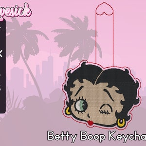 Może przedstawiać: Brelok do kluczy z Betty Boop w kolorze czerwonym i czarnym z mrugającym okiem. Brelok jest zawieszony na czerwonej sznurce z sercowatą pętelką u góry.