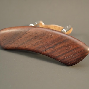 Pode incluir: Um apoio de ombro para violino de madeira marrom escuro com ferragens de metal prateado.