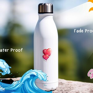 Peut inclure: Gourde blanche avec un couvercle argent&eacute;, orn&eacute;e d'un autocollant de deux c&oelig;urs rouges. Les mots "Water Proof" et "Fade Proof" sont visibles. L'arri&egrave;re-plan pr&eacute;sente une vague oc&eacute;anique stylis&eacute;e et un cadre naturel flou.