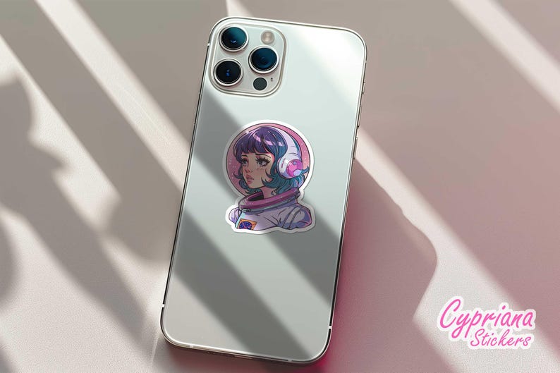 May include: A sticker featuring a cartoon illustration of a girl with purple hair wearing a white astronaut suit and headphones. The background is a pink and purple galaxy. The sticker is on a white iPhone.