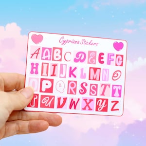 Könnte beinhalten: Ein rechteckiges Stickerbogen mit dem Alphabet in verschiedenen Rosa- und Rottönen. Die Buchstaben sind im Ausschnitt-Stil gehalten, wobei jeder Buchstabe eine andere Schriftart hat. Das Stickerbogen hat zwei rosa Herzdesigns und den Text "Cypriana Stickers".