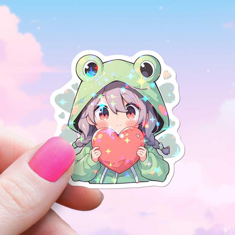 Pode incluir: Um adesivo com uma menina de desenho animado vestindo um moletom verde de sapo e segurando um cora&ccedil;&atilde;o rosa. O adesivo tem um acabamento hologr&aacute;fico.