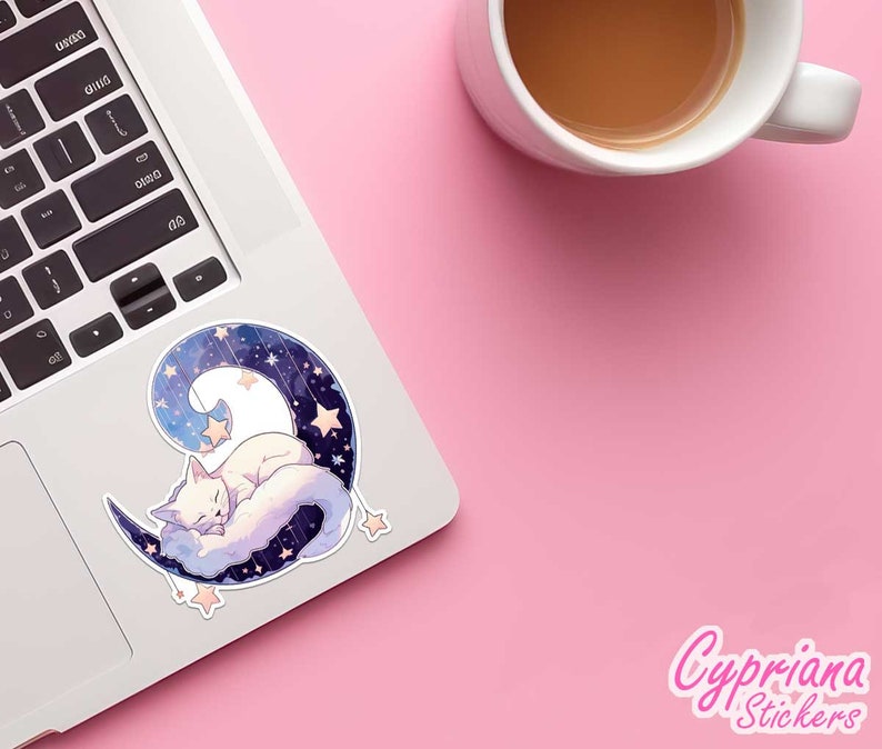 May include: A white cat sleeps on a crescent moon with a starry sky background. The moon is blue and purple with white stars. The cat is curled up on the moon with its eyes closed. The sticker is on a laptop.