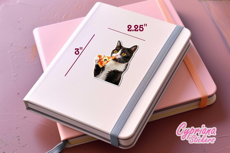 以下が含まれることがあります： 白のノートに、ピザを食べる白黒猫の7.6cmのステッカー。ステッカーの幅は5.7cmです。ノートはピンクのノートの上にあります。画像には「Cypriana Stickers」というテキストが含まれています。