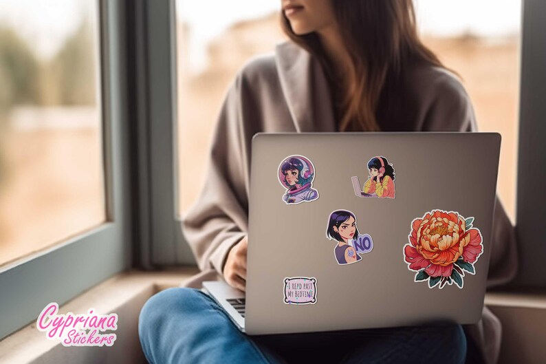 May include: A silver laptop computer with several stickers on the lid. The stickers feature illustrations of people wearing headphones, a flower, and text that says "I keep part of my routine".
