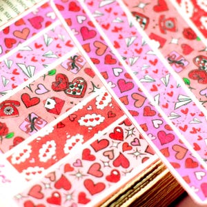 May include: A collection of decorative sticker strips with Valentine's Day themes. The strips feature various patterns of hearts, gifts, roses, and paper airplanes in shades of pink and red. The text "Cypriana Stickers" is visible.
