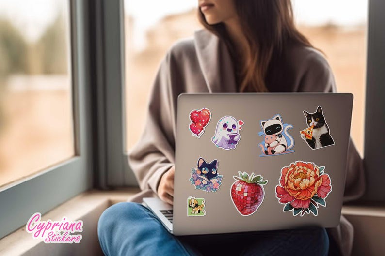 Peut inclure: Un ordinateur portable orn&eacute; d'autocollants color&eacute;s. On y trouve un c&oelig;ur rouge, un fant&ocirc;me, un panda avec un cochon, un chat noir et blanc mangeant une pizza, un chat noir dans des fleurs, une fraise et une grande fleur.