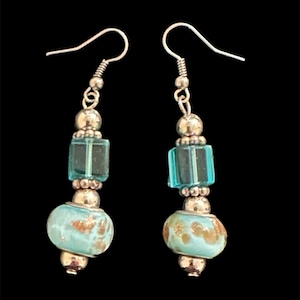 Può includere: Un paio di orecchini pendenti in argento con perline di vetro blu turchese e distanziatori in argento.