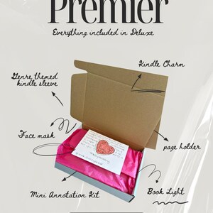May include: A brown cardboard box containing bright pink tissue paper and a white note with a red heart illustration. Text labels point to items including a genre themed kindle sleeve, kindle charm, page holder, face mask, book light, and mini annotation kit.