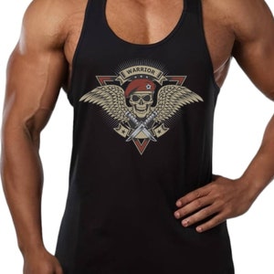 Op de afbeelding: Zwart tanktop zonder mouwen met een schedel- en vleugelmotief. Het motief toont een schedel met een rode baret, gekruiste messen en het woord "Warrior" in een banner boven de schedel.
