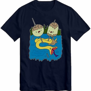 May include: A navy blue t-shirt featuring a graphic of two green and brown cartoon characters with googly eyes and a yellow snake with a purple tongue. The characters are on sticks and the snake is in the water.