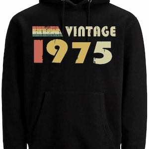 May include: Black hooded sweatshirt with a vintage 1975 design in rainbow colours. The text "Vintage" is above the year.