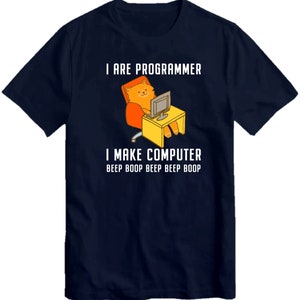 May include: A navy blue t-shirt with a cartoon cat sitting in a chair and using a computer. The text on the shirt reads "I are programmer I make computer beep boop beep beep boop".