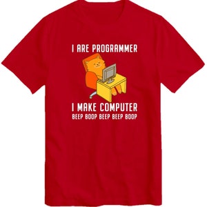 May include: Red t-shirt with a cartoon cat sitting at a computer. The text on the shirt reads "I are programmer I make computer beep boop beep beep boop".