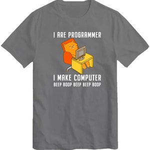 May include: A gray t-shirt with a cartoon cat sitting in a chair and using a computer. The text on the shirt reads "I are programmer I make computer beep boop beep beep boop".