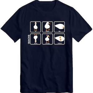 Könnte beinhalten: Ein marineblaues T-Shirt mit einer weißen Grafik einer Gans in verschiedenen Positionen. Die Grafik ist mit dem Wort "QUACKS" beschriftet und die Positionen der Gans sind mit "up", "charm", "top", "down", "strange" und "bottom" beschriftet.