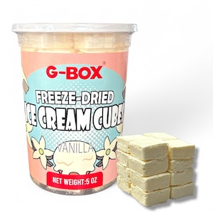 May include: A clear plastic tub of G-Box freeze-dried vanilla ice cream cubes. The container has a pink and blue label with the text "FREEZE-DRIED ICE CREAM CUBES" and "VANILLA". The net weight is 142 grams. Several vanilla ice cream cubes are stacked next to the container.