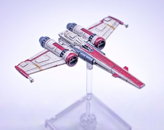 Puede incluir: Una nave espacial de caza estelar blanca y roja con detalles negros y grises. La nave espacial está en un soporte de plástico transparente.