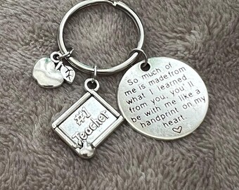 May include: Silver keychain with a small chalkboard charm that says "#1 Teacher" and a round charm with the text "So much of me is made from what I learned from you, you'll be with me like a handprint on my heart."