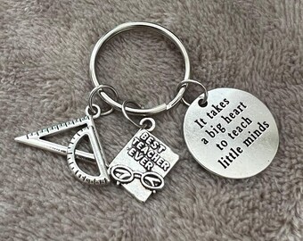 May include: Silver keychain with a charm that says "Best Teacher Ever" and a charm that says "It takes a big heart to teach little minds".