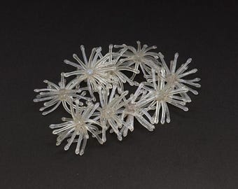 May include: A cluster of translucent, clear plastic decorative elements, each shaped like a multi-pointed star or sea anemone with radiating, thin, rounded arms extending from a central point, arranged in a loose, overlapping group.