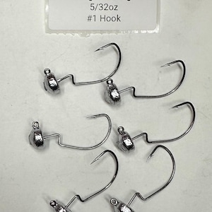 May include: Six weedless Neg Head Jigs with a 5/32oz weight and #1 hook. Each jig features a silver-colored head and a curved hook. A white label in the background reads "Weedless Neg Head Jig 5/32oz #1 Hook."