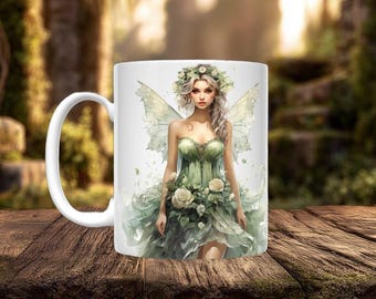 May include: A white ceramic mug featuring a printed illustration of a fairy with long light hair, wearing a green dress adorned with white roses and leaves, and sporting translucent wings, with a floral crown resting upon the fairy's head.