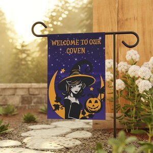 May include: A rectangular garden flag featuring a dark purple night sky with stars, a large yellow crescent moon, and a witch wearing a pointed hat. The text reads WELCOME TO OUR COVEN in yellow letters, accompanied by a smiling jack-o'-lantern.