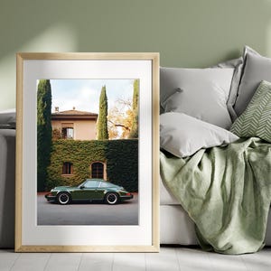 Elegant photograph of a green Porsche 911 parked in front of an ivy-covered Italian villa with cypress trees — luxury car wall art print.