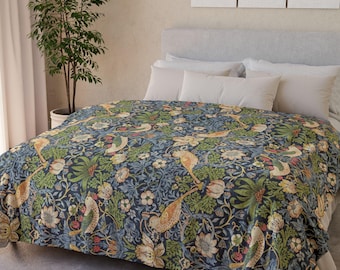 May include: A blue, green, and yellow floral patterned blanket on a bed. The blanket features a repeating design of birds, flowers, and foliage. The bed has white pillows and a gray headboard. The room has a neutral color scheme.