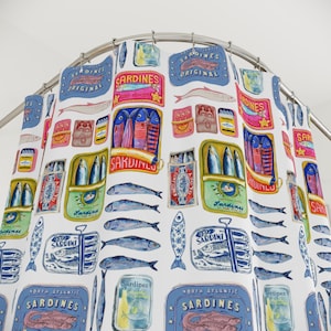 May include: A white shower curtain featuring a repeating pattern of sardines and sardine cans in various colors. The design includes blue, pink, yellow, and green elements, with the word "Sardines" prominently displayed.