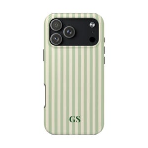 May include: A phone case with a vertical striped pattern in light green and cream. The case has a black camera module with three lenses and the initials "GS" in a dark green font.