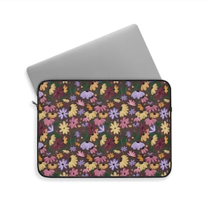 May include: A laptop sleeve with a floral pattern. The sleeve is brown with a repeating pattern of colorful flowers in shades of yellow, pink, purple, and burgundy. A silver laptop is partially inserted into the sleeve.