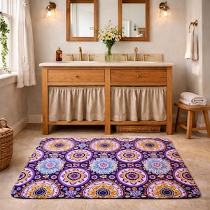 May include: A rectangular bathroom rug featuring a repeating pattern of circular floral motifs in shades of purple, orange, yellow, and light blue. The rug has a soft, plush texture and is positioned on a light-colored tiled floor.