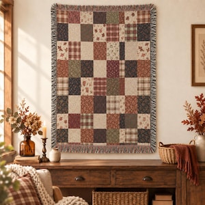 Peut inclure: Un plaid tissé présentant un motif patchwork composé de blocs rectangulaires dans des tons automnaux variés, notamment rouge profond, vert forêt, bleu marine et crème, avec des bords à franges et des motifs à carreaux, floraux et feuillages.