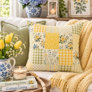 May include: A square throw pillow featuring a patchwork design of yellow and green fabrics with floral, gingham, and striped patterns. The pillow is displayed on a white sofa alongside a solid green pillow and a yellow knit throw blanket.