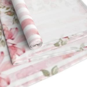 May include: Pink and white striped fabric with a floral pattern. The fabric is rolled up and the floral pattern is visible on the outside of the roll.