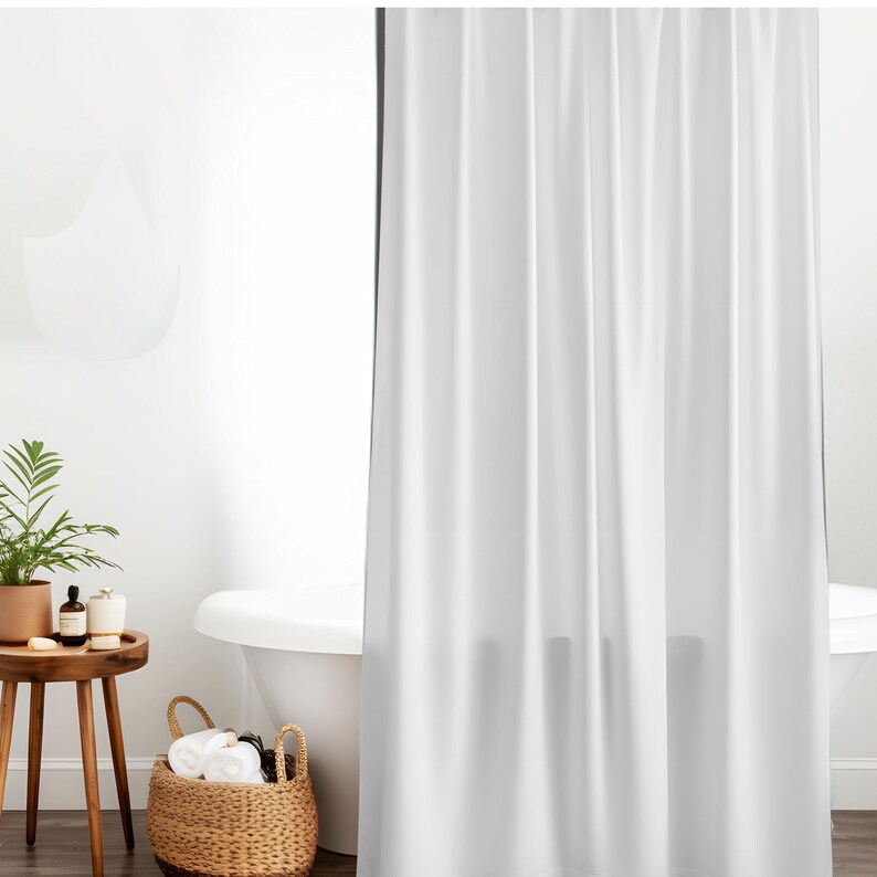 May include: A white shower curtain hangs in a bathroom setting. A small wooden side table holds a potted plant and toiletries. A wicker basket with towels sits near a white bathtub, creating a clean and minimalist aesthetic.