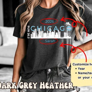 Pode incluir: T-shirt cinza escuro mesclado com um gráfico do horizonte de Chicago. O design inclui a palavra "Chicago" em azul, o ano "2026" e o nome "Sarah". A camisa também apresenta um tênis de corrida e a bandeira de Chicago.